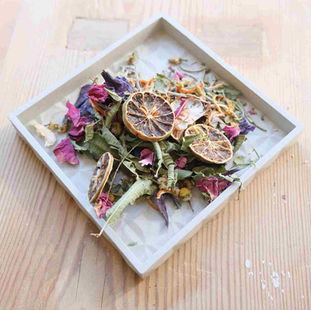 small concrete tray with potpourri ingredients such as dried flowers herbs and slice of lemon
