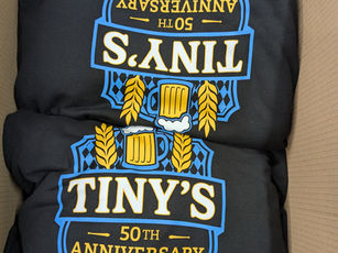 Box of new custom ordered hoodie sweatshirts with multicolor screen-print on the front advertising a local business.