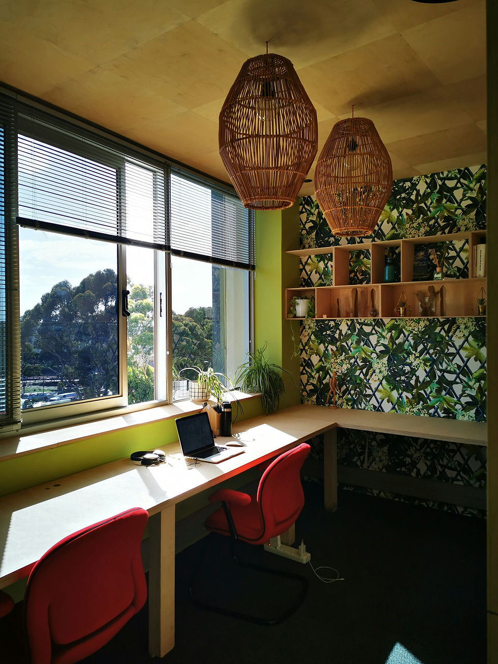 A modern office corner with leaf-patterned wallpaper