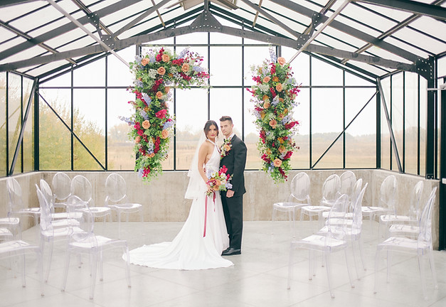 Bride and groom framed by elegant ceremony flowers in a timeless wedding photographed by Baskin Creative Co., a Canadian wedding photographer.