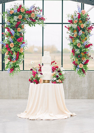 Wedding ceremony flowers thoughtfully repurposed for the cake table display during a luxury wedding reception photographed by Baskin Creative Co., a Canadian wedding photographer.