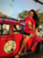 Woman in red shirt leaning on red Volkswagen Beetle