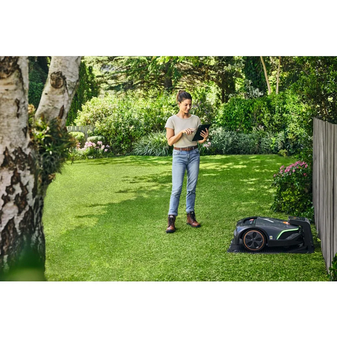 Frau steuert Husqvarna Rasenroboter mit Tablet