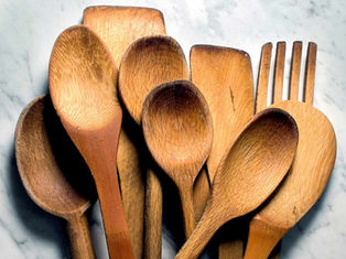 Kristina Lavallee standing in a kitchen holding a wooden spoon and cutting board, as featured in Southern Living’s article about proper care for wood-based kitchenware.