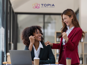 Two female corporate professionals happily talking in the office