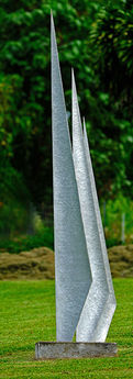A tall aluminum abstract sculpture that looks something like the sails of a ship.