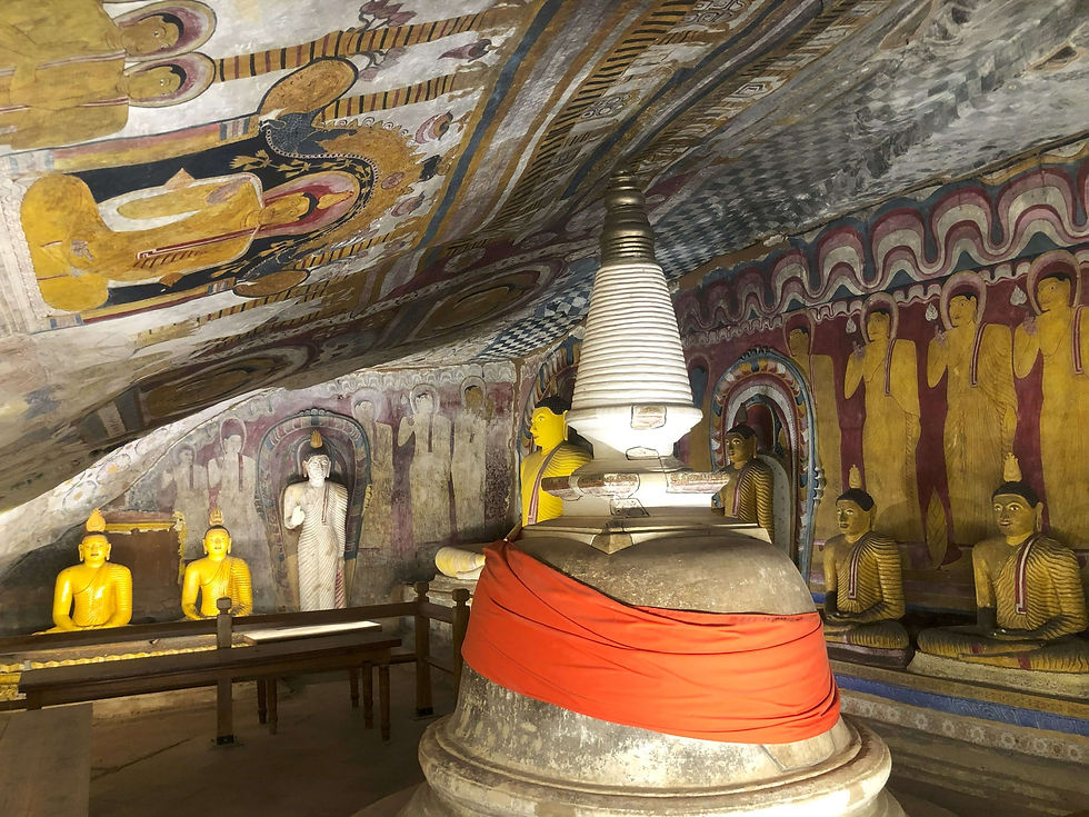 Inside cave 4 at Dambulla Cave Temple Buddha statues and painted figures in a cave temple with vibrant murals. Central stupa wrapped in orange cloth. Peaceful, sacred ambiance.