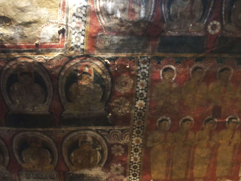 Colourful Buddhist murals with seated figures, halos, and ornate patterns on a temple wall. Red, gold, and black hues create a serene atmosphere.