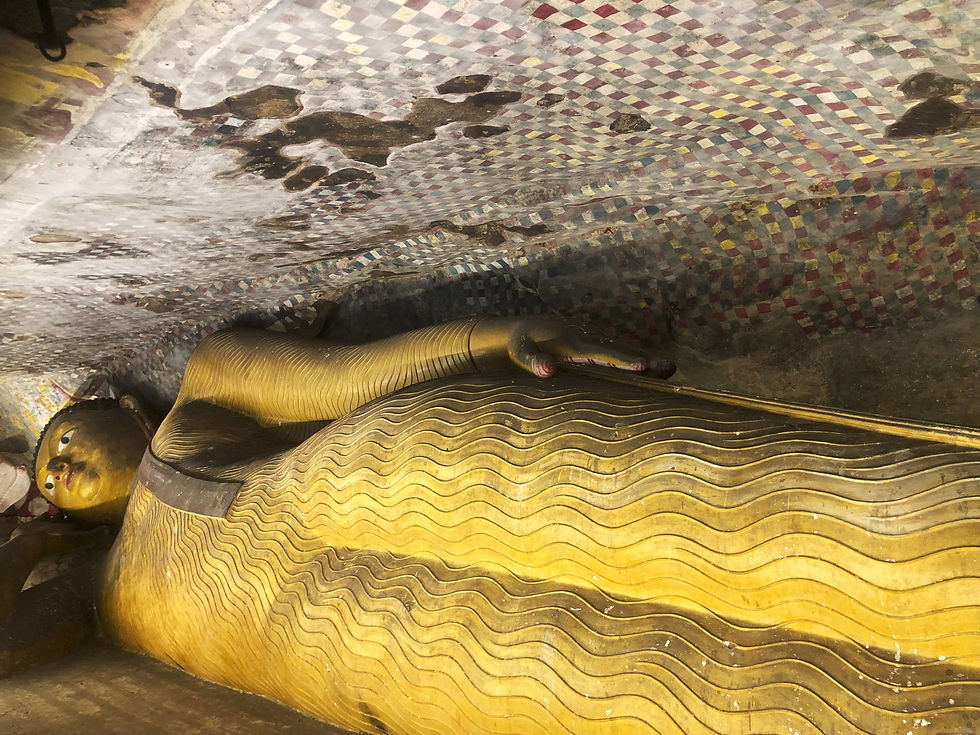 Reclining Buddha statue with golden, wavy patterns; mosaic ceiling above in various colors at the Dambulla Cave Temple