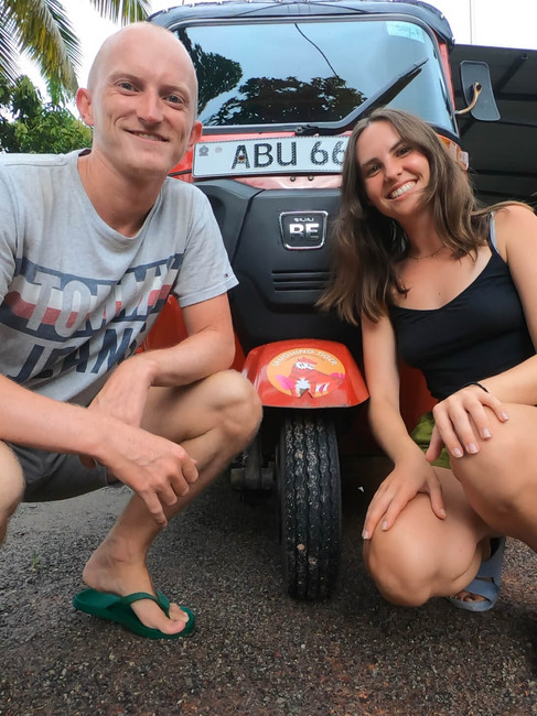 Kate and Mike knelt down in front of a tuk tuk
