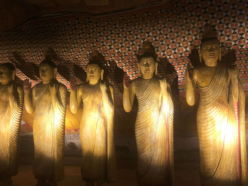 Five Buddha statues with raised hands are lit in a dim room. The background features a colorful, geometric pattern on the ceiling.