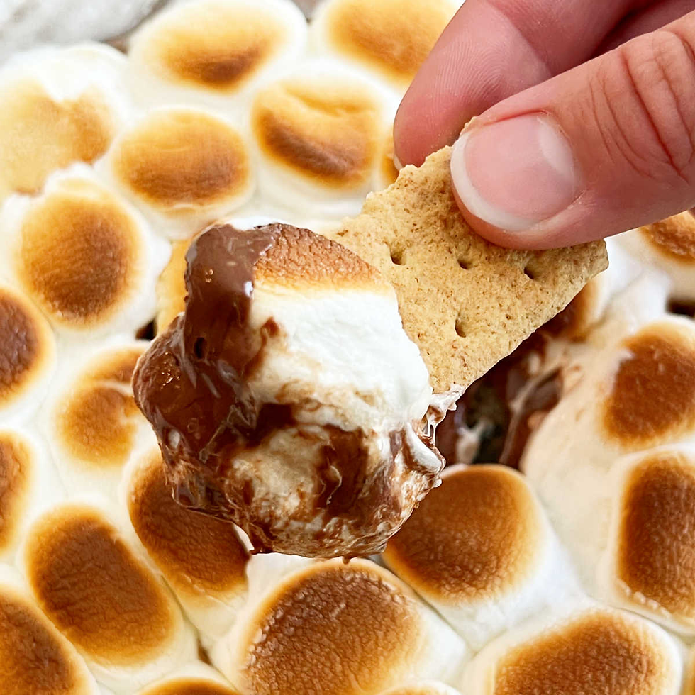 Gooey s'mores dip in a skillet with melted chocolate and toasted marshmallows, perfect for dipping graham crackers.
