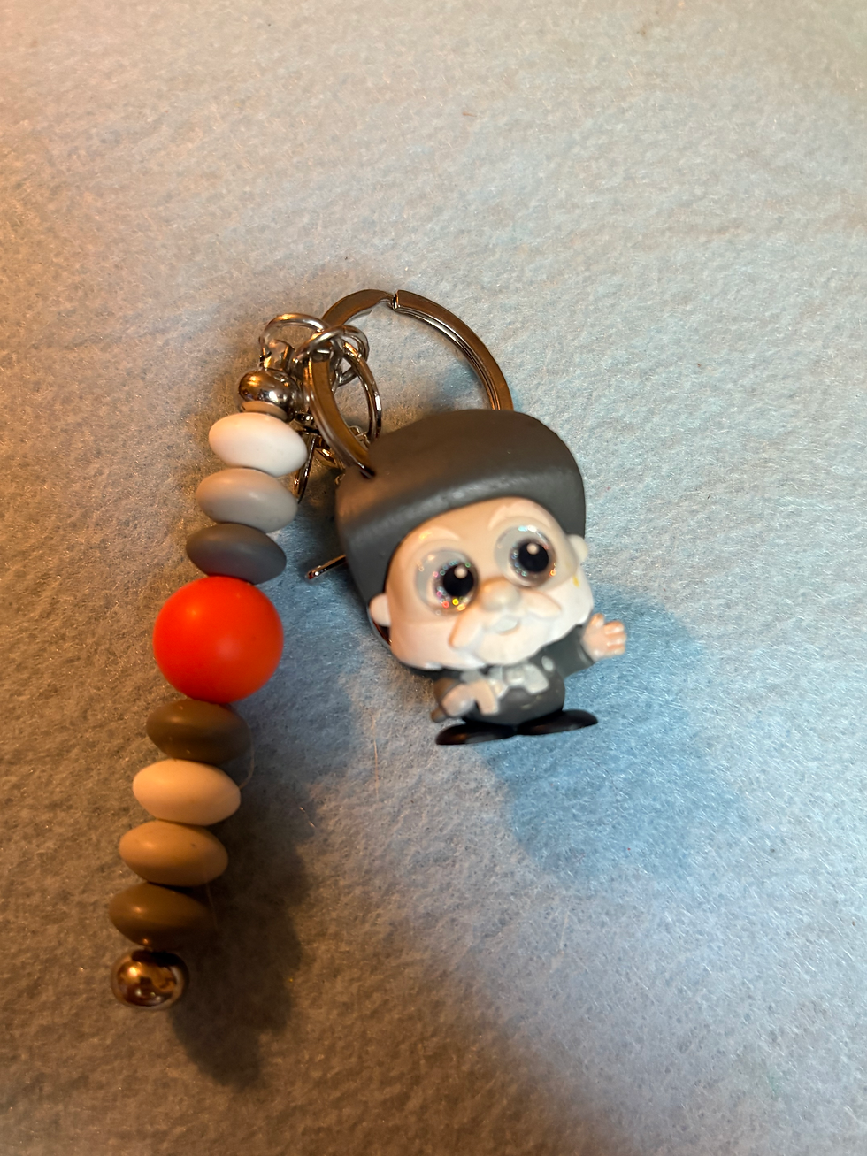 Thumbnail: Keychain with elderly man figure, grey hat, glasses, and beaded string.