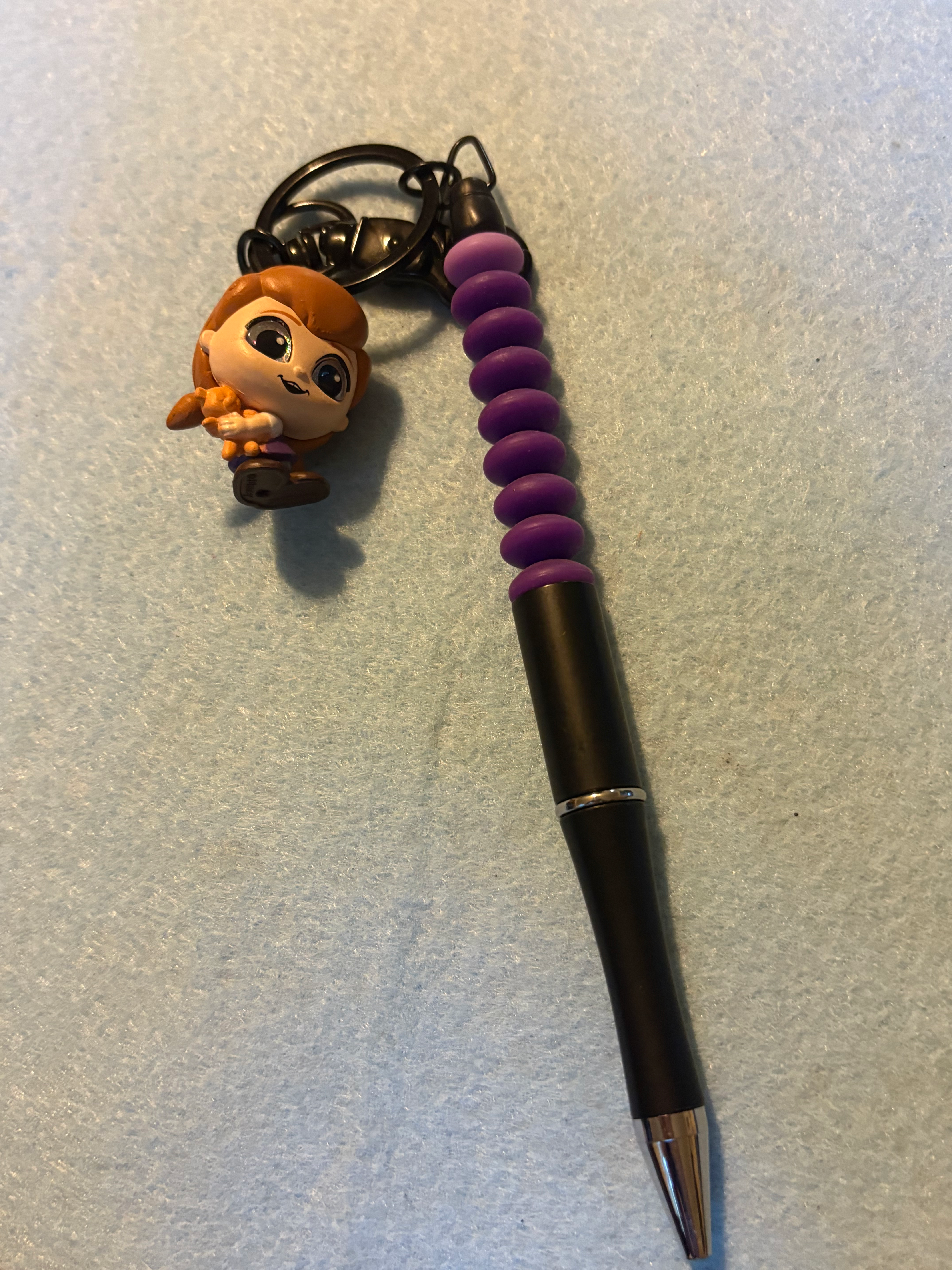Anna figurine keychain attached to black stylus with purple grip.