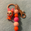 Thumbnail: Rose gold keychain with orange cartoon rabbit figure and vibrant beaded lanyard.