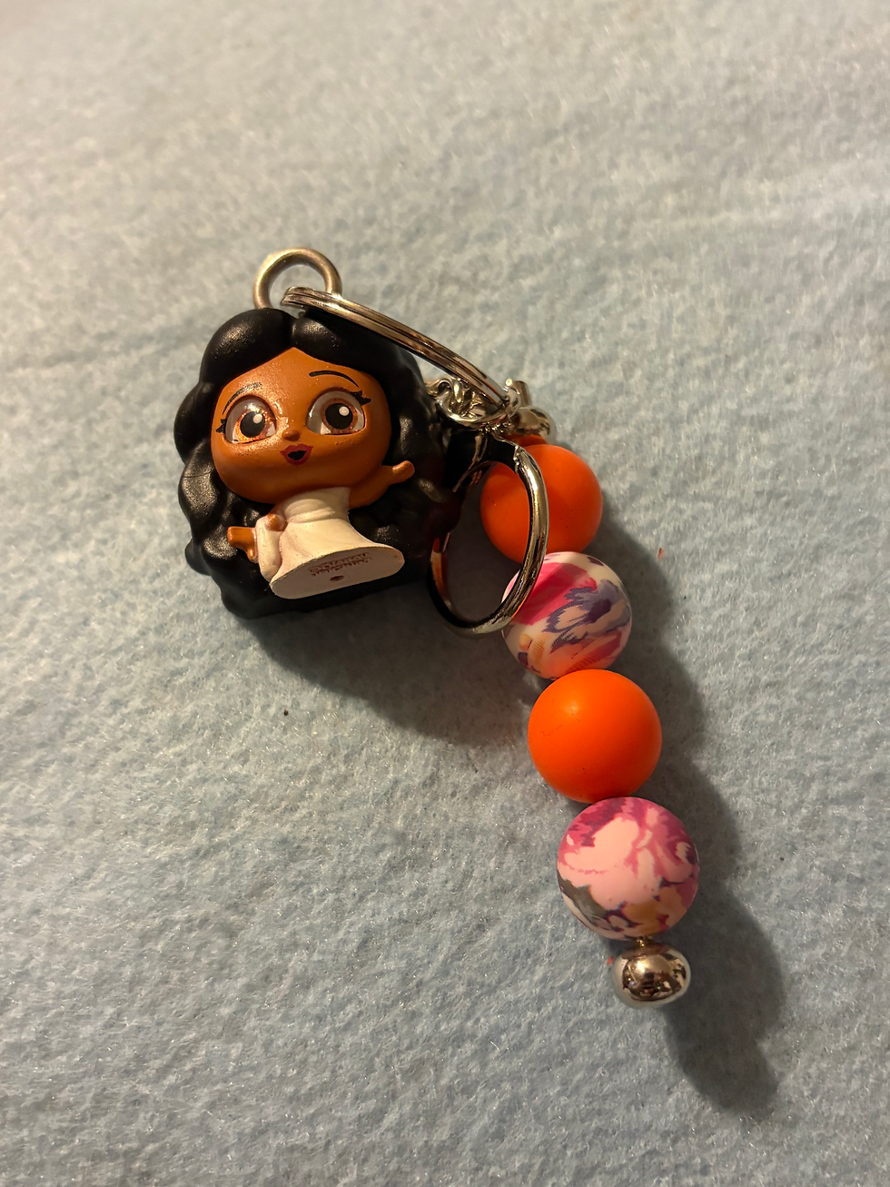 Thumbnail: Keychain with small cartoon doll, orange and marbled pink beads.