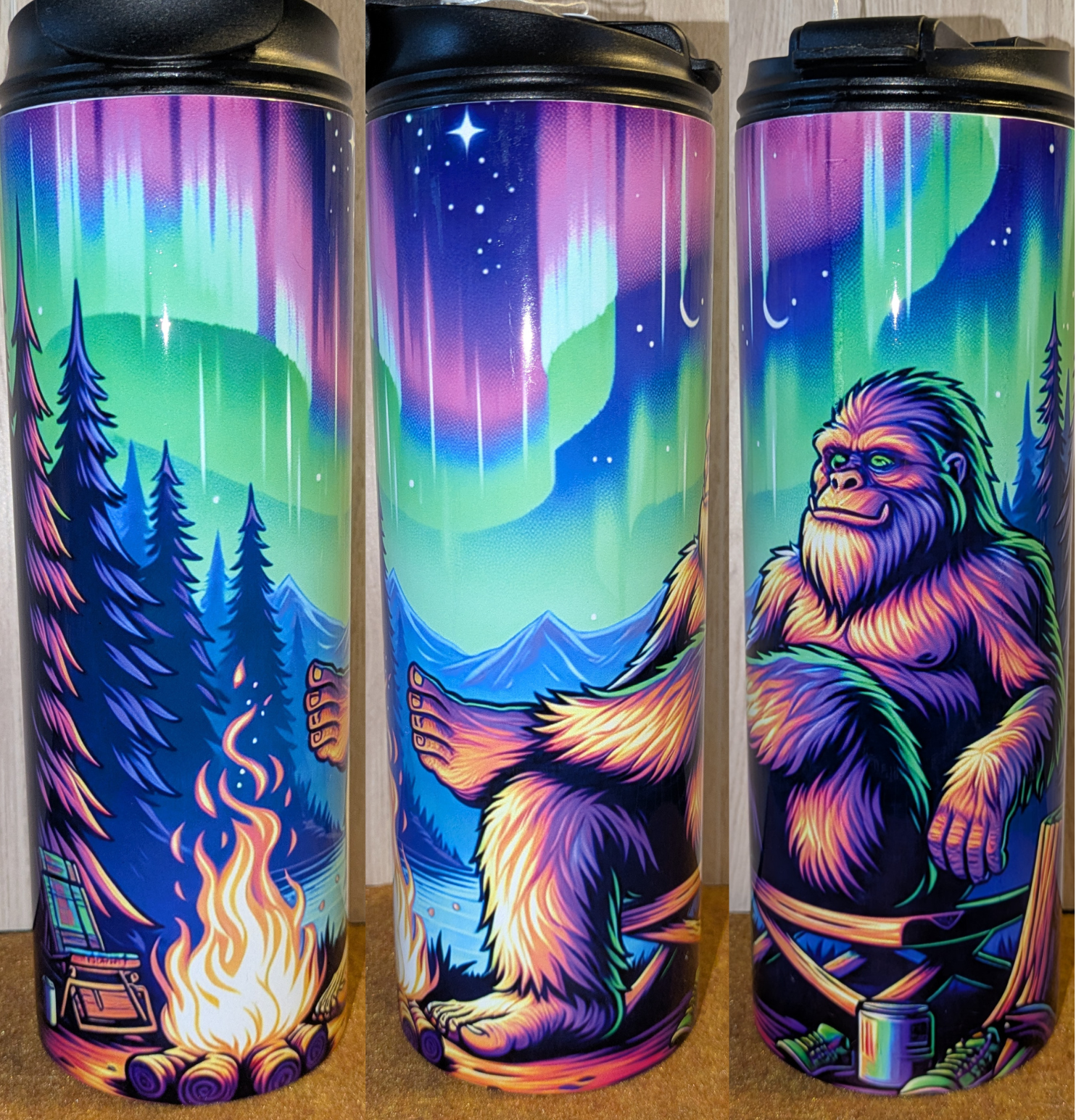 Colorful tumbler with Bigfoot sitting under northern lights and campfire.