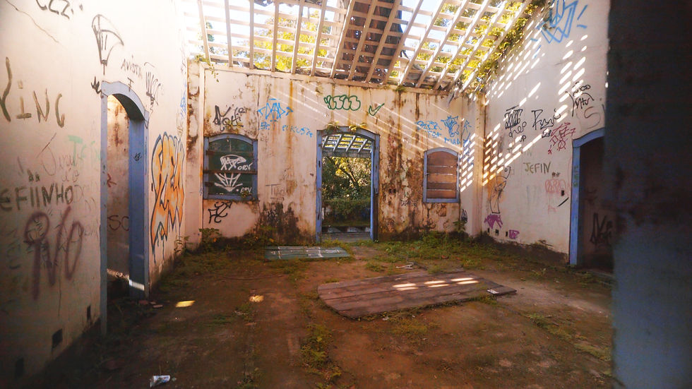 Uma casa grande abandonada em cena do documentário brasileiro Paraíso (2024), de Ana Rieper. Na imagem, a habitação tem as paredes brancas internas pichadas, janelas e portas caídas e somente a estrutura do telhado sem telhas.