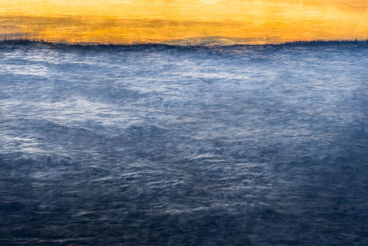 Dark blue sea with a strong line as the horizon. Above the horizon there is deep warm strong yellow sky. Nordic summer night sky. Fine art photography by Päivi Maria Wells.