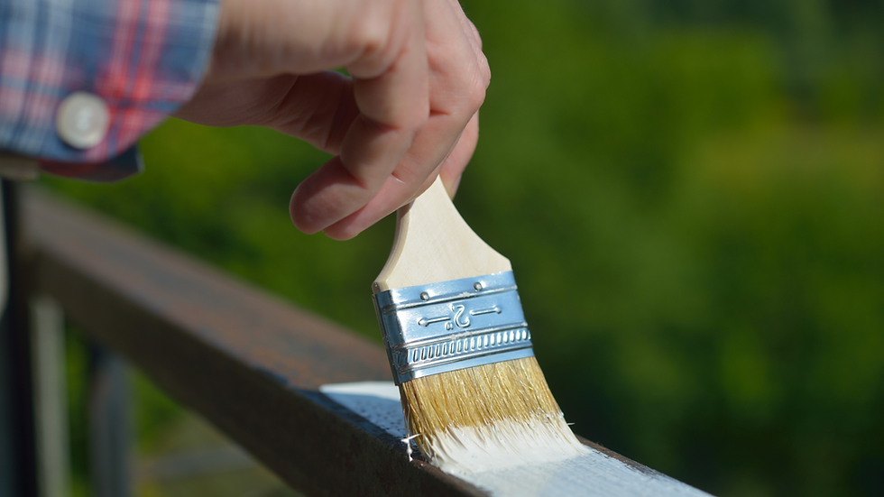 a man brushes white paint on an exterior railing