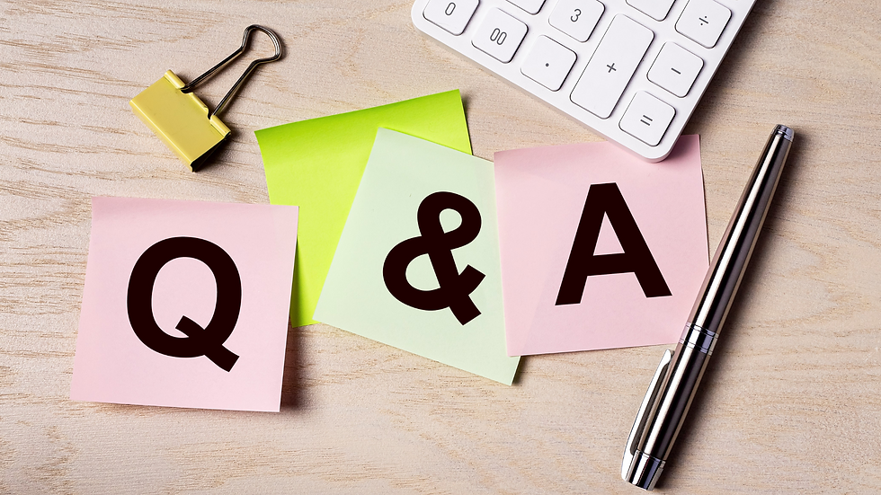 Sticky notes with "Q & A" on a wooden desk. Includes a pen, yellow binder clip, and part of a white keyboard. Bright and organized setting.