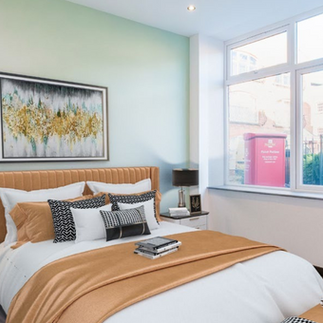 Modern bedroom with large window, gold bedding