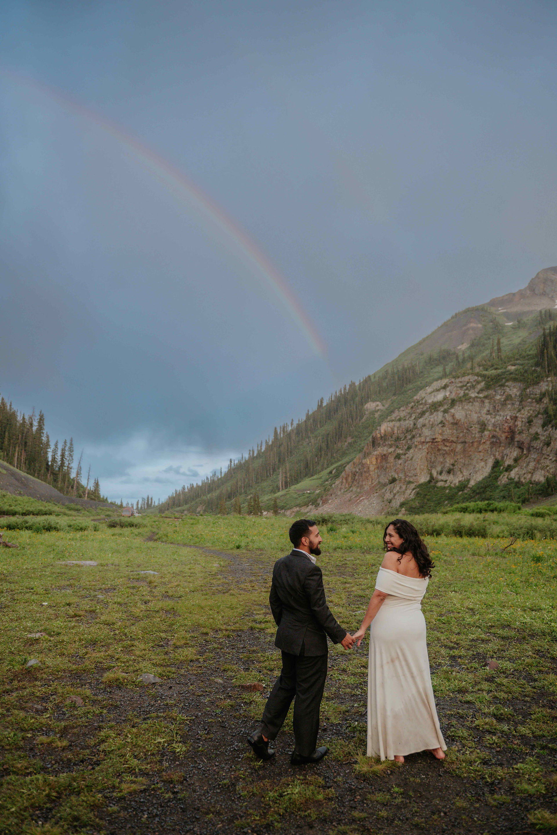couple holding hands under a rainbow