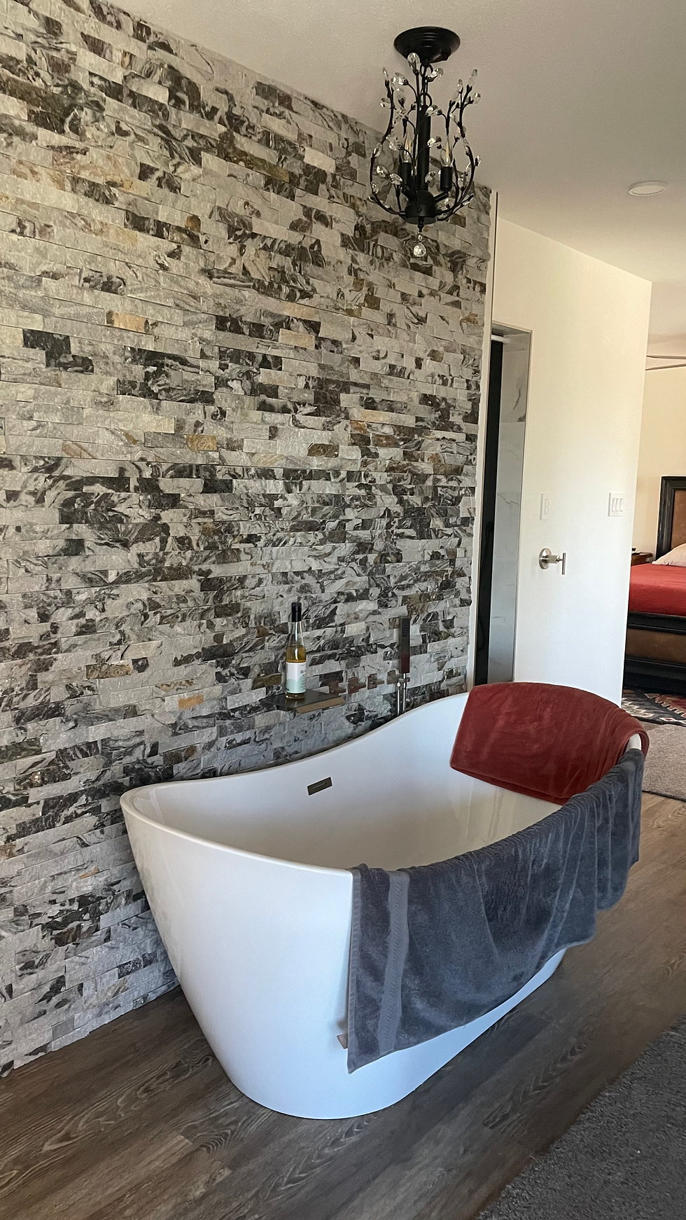 Bathroom with a stacked-stone accent wall and freestanding tub