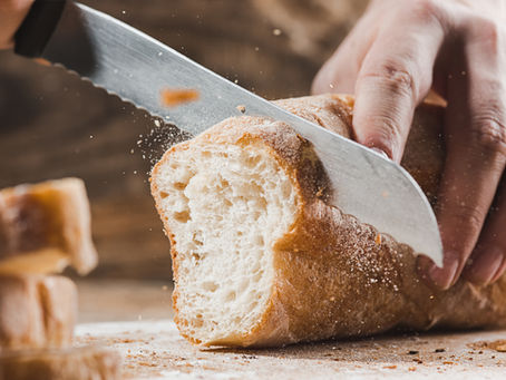 A loaf of bread being sliced by a knife