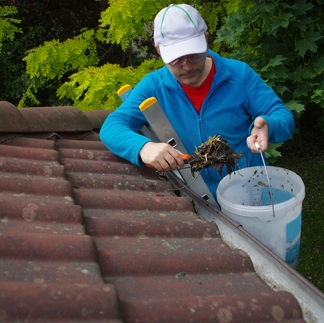 Removing debris from the gutters on a roof.
