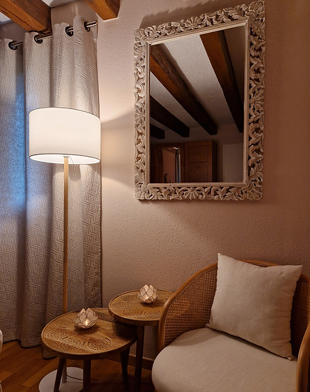 fauteuil et deux tables basses à côté d'une lampe avec un miroir accroché au mur