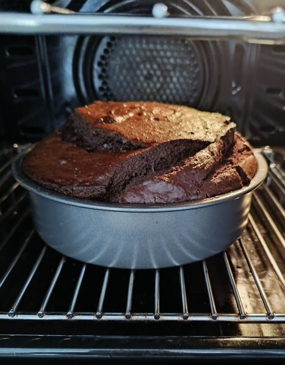Open oven with thick moist chocolate cake that has split showing the lushness of the cake
