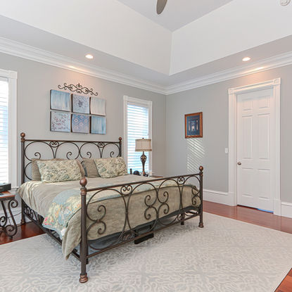 Bedroom with ornate iron bed, patterned bedding, and white door
