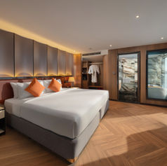 Well-appointed luxury cabin on Luna Halong Cruise with king bed, warm lighting and floor-to-ceiling bay windows
