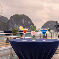 Elegantly set dinner table on Luna Halong Cruise with red rose décor and evening lighting

