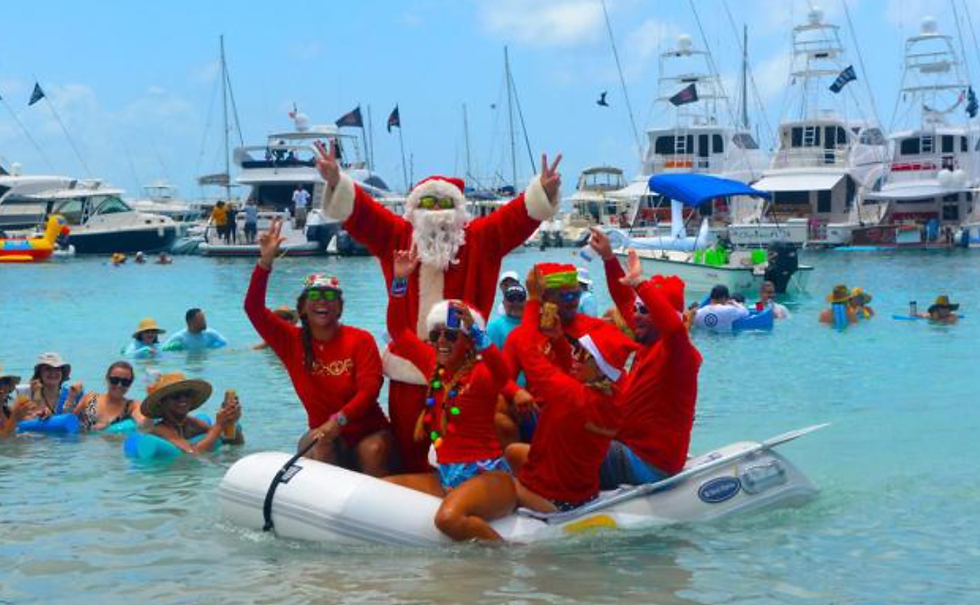 roup of people dressed as Santa Claus celebrating Christmas in July on a dinghy in turquoise waters of the BVI
