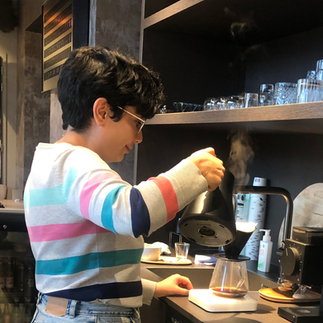 female figure pouring water too filter coffee in coffee bar