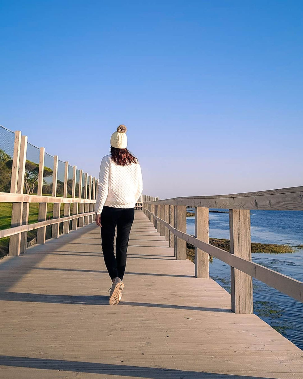 Girl walking on a board walk along the sea