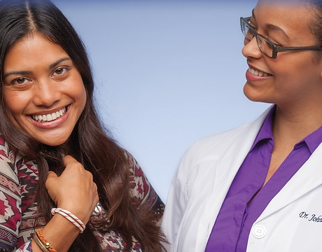An orthodontist is smiling at patient who is showing her beautiful smile.
