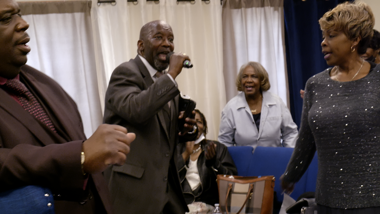 Pastor to Katherine Massey, Alan Core, preaching at his Church.png