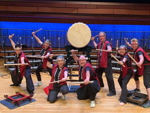7 Taiko players pose for a photo with their drums on stage