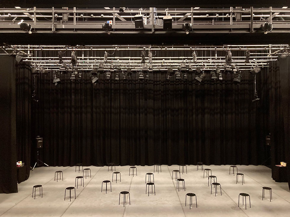 A large empty stage with a grey dance-floor underneath a lighting rig