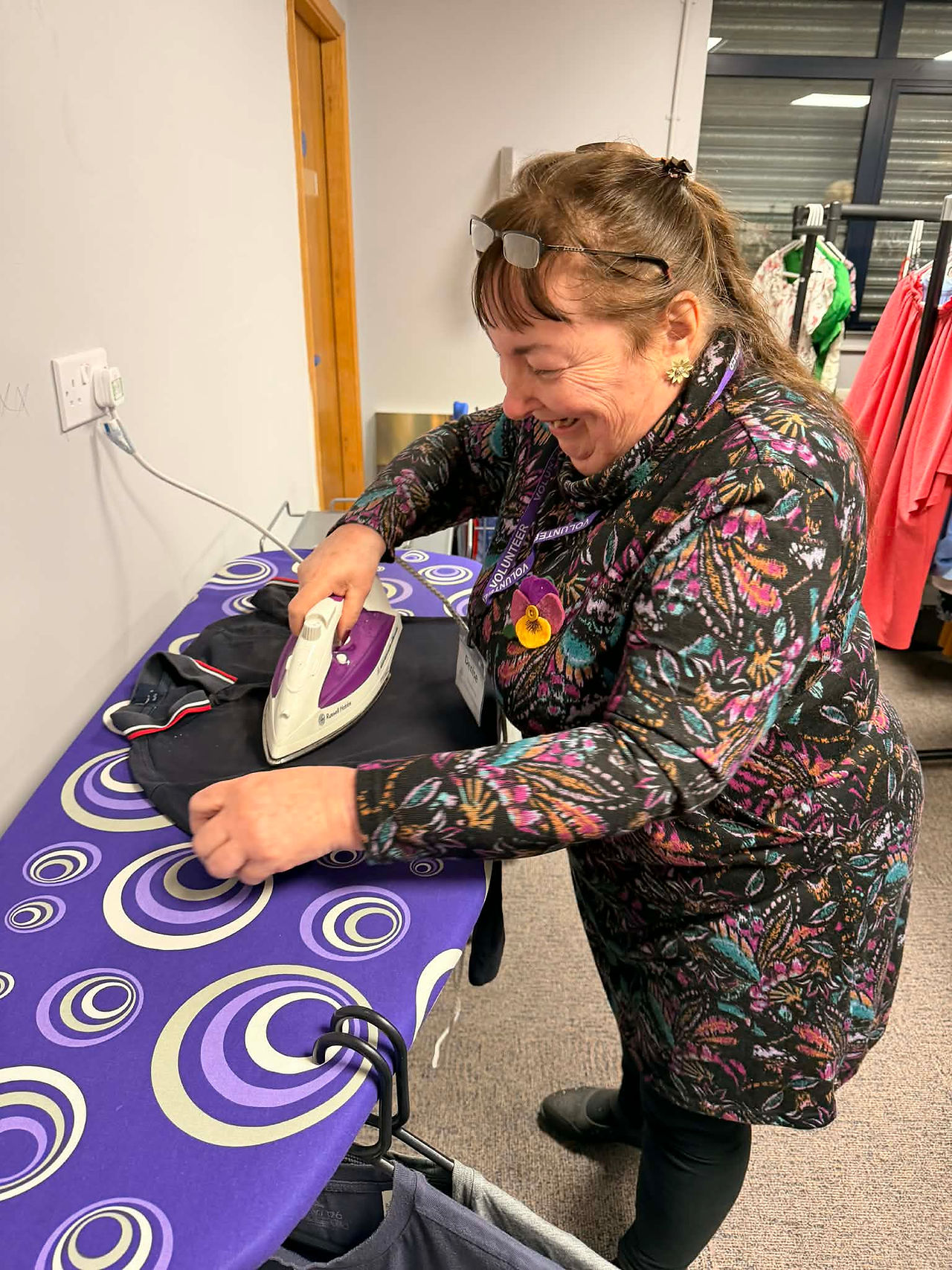 Lady volunteer ironing clothes before putting bthem on display