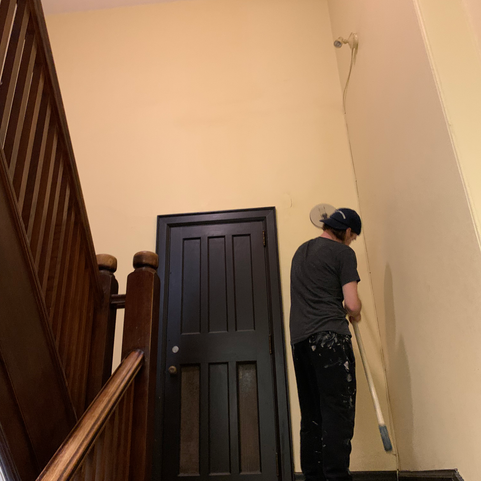 EZ Paint employee sanding walls before painting. Protective material on the floor.