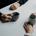 Table, with two people only hands visual, holding a cup of tea each