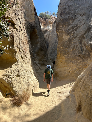A person wearing a blue hat and dark clothing looking ahead as they wall into Annie's slot canyon.
