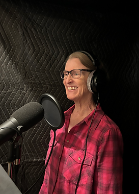 A smiling Lea Appleton is wearing headphones and inside a recording booth.