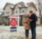 A young couple stands in front of a home during the late fall or early winter, with colorful fallen leaves and light snow on the ground. Next to them is a "For Sale" sign clearly marked with a red circle that says "PRICE REDUCED - MOTIVATED SELLER" and indicates "DAYS ON MARKET: 95." The image illustrates the ideal time and scenario (slower season and long-lingering listing) for buyers to find a deal.