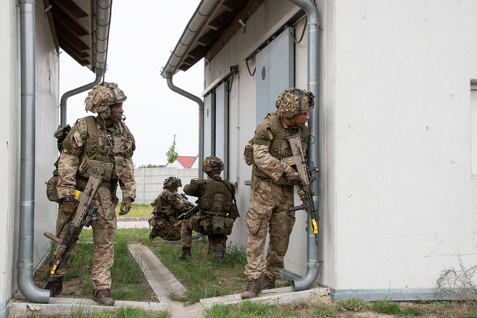 Soldiers in camouflage gear near a building, UK during a training exercise.