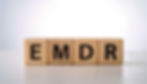 Wooden blocks spell "EMDR" in bold black letters on a white surface, set against a soft white background.